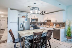 A modern kitchen with a central island, stainless steel appliances, and a decorative backsplash. - Wharftown Retreat at Laketown Wharf 3BR Condo w/ Balcony Views, Pools, Walk to Beach, Sleeps 8 | Daily Entry to Local Activity Options (Panama City Beach)