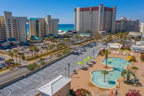 A hotel with a pool area, parking, and a view of the ocean.