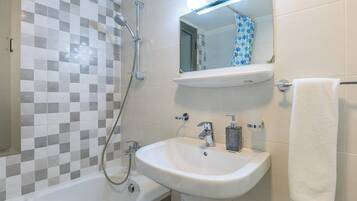 Un baño con bañera, lavamanos, ducha y espejo.