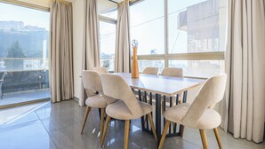 A modern dining area with a rectangular table and six chairs, large windows with curtains, and a view of the cityscape. - Elevate - Sleek 2-BR Apt by Santa Maria, Jal el Dib (Jal El Dib)