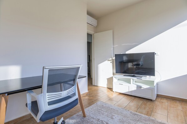 A modern living room with a flat-screen TV, a white entertainment unit, and a chair.