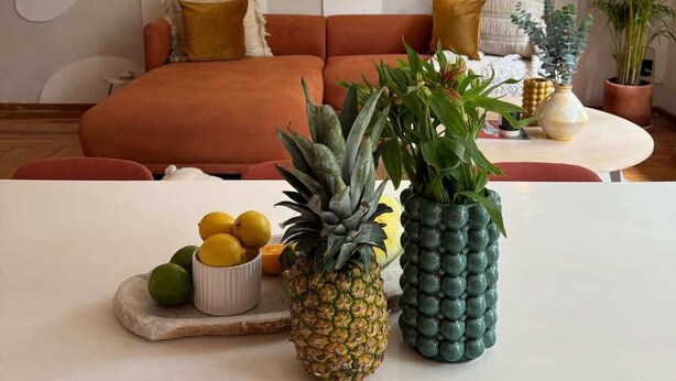 Ein Wohnzimmer mit einer Couch, einem Couchtisch mit Früchten und Wandleuchten.