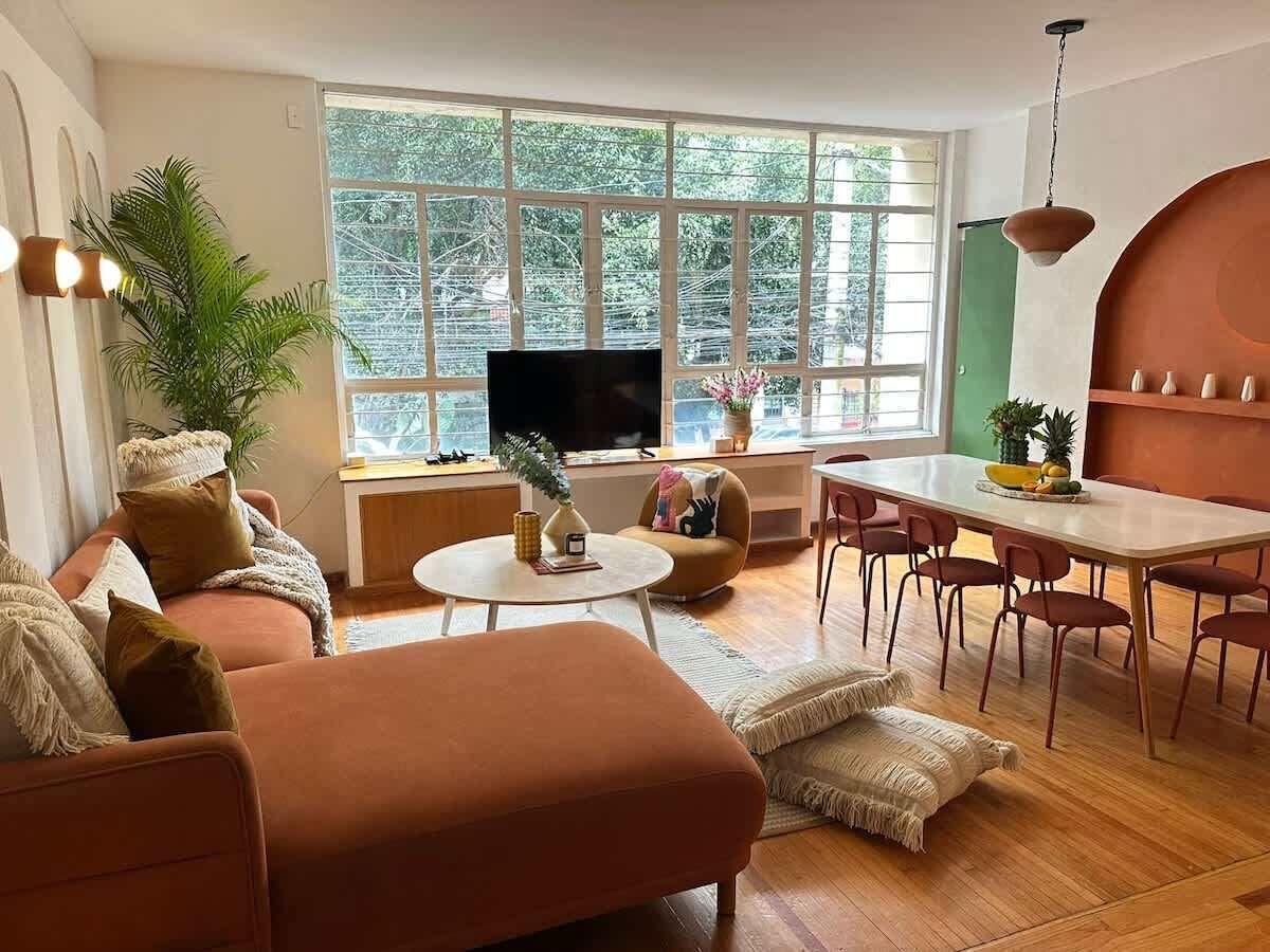 A modern living room with a sofa, coffee table, and dining area.