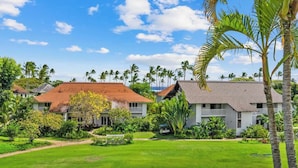 A resort with two-story buildings, a well-maintained lawn, and palm trees.