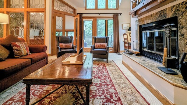 A spacious living room with a fireplace, large windows, and a cozy seating area. - Slopeside Condo w/ Private Hot Tub – Steps to Peru Lift & Ski School (Keystone)