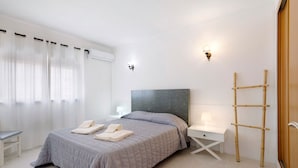 Une chambre d’hôtel équipée d’un lit, d’une table de chevet, d’une lampe, d’un climatiseur et d’une échelle en bois.