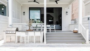 A covered outdoor area with a pool, white chairs, and a grill. - The 1300 | 4 Home Combo, 28 bedrooms | Heated Pool (New Orleans)