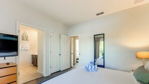 Une chambre d’hôtel avec un grand lit, une télévision, un bureau avec des tiroirs et une salle de bain visible à travers une porte ouverte.