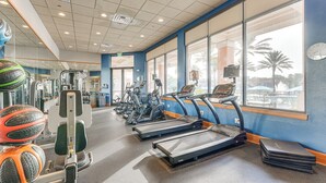 Une salle de sport équipée de tapis de course, de vélos elliptiques et de matériel de musculation.