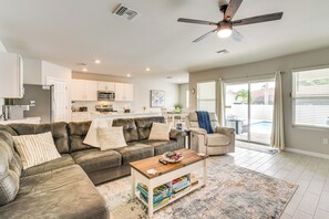 A modern living room with a leather couch, a wooden coffee table, and a view of the backyard through large sliding glass doors.