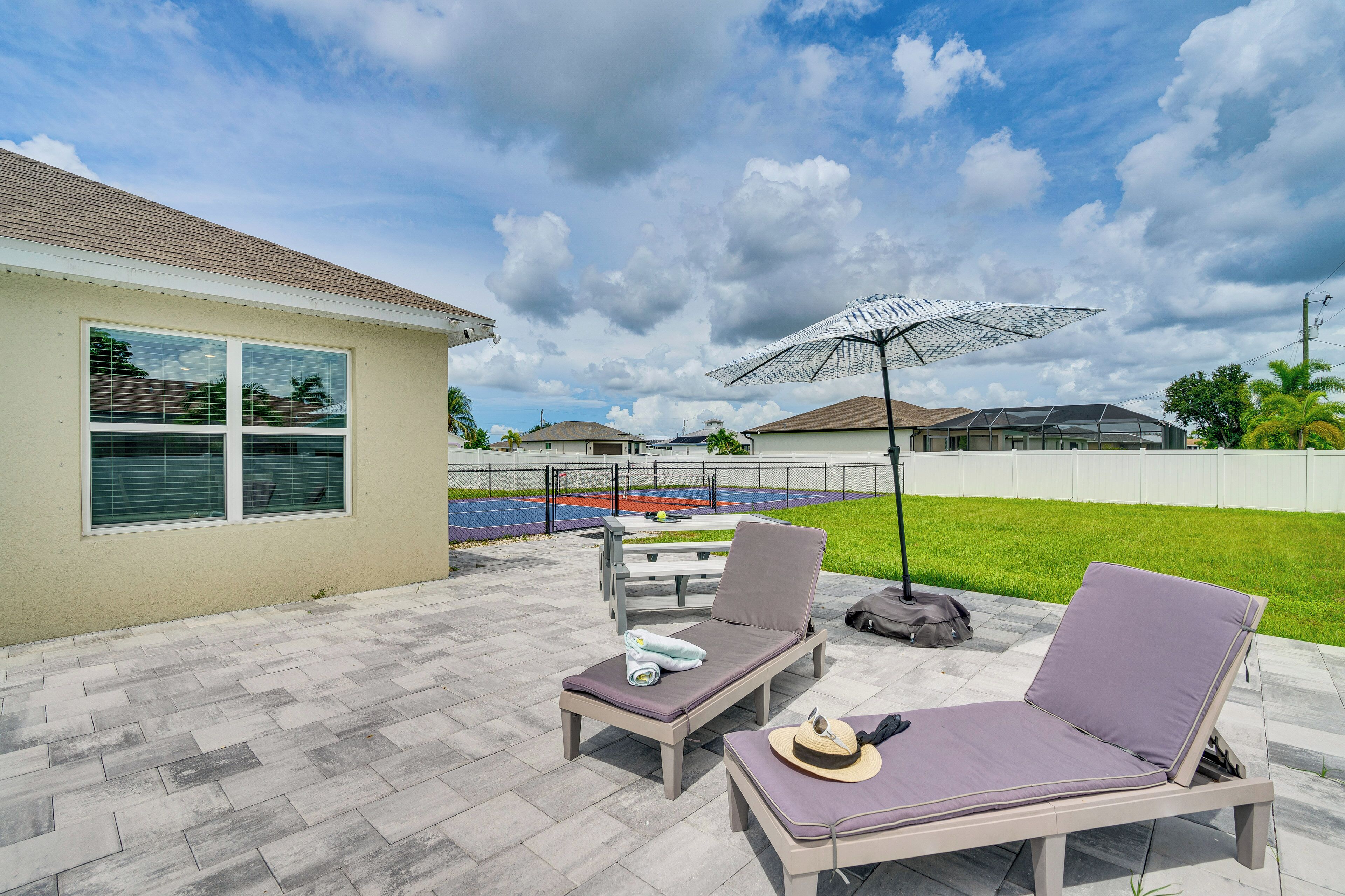 A patio with two lounge chairs, a table, and an umbrella.