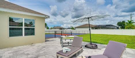 A patio with two lounge chairs, a table, and an umbrella.