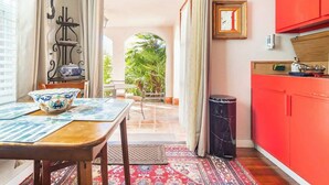 A kitchen with a red cabinet, a dining table with a blue and white patterned tablecloth, and a view of a patio with palm trees. - Serene Private Suite Patio ~ Upscale Berkeley (Berkeley)