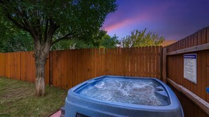 Ein Whirlpool in einem Garten mit Holzzaun und Baum.