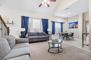 A living room with a sofa, coffee table, and dining area with chairs and a table. - Spacious 5-BD/3-BA Forest View Getaway (Sleeps 13) (Dallas)