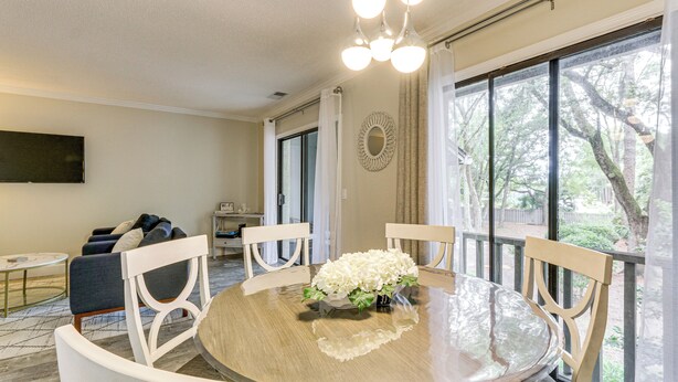 A dining area with a round table, white chairs, and a floral centerpiece.