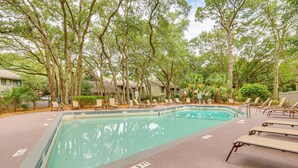 A swimming pool surrounded by lounge chairs and trees.