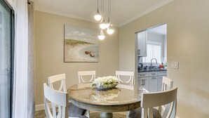 A dining area with a round table, white chairs, and a bowl of flowers.