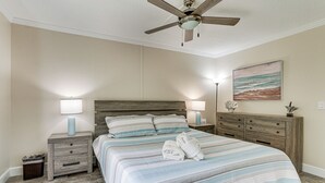 A bedroom with a bed, nightstands, a ceiling fan, a lamp, and a painting on the wall.