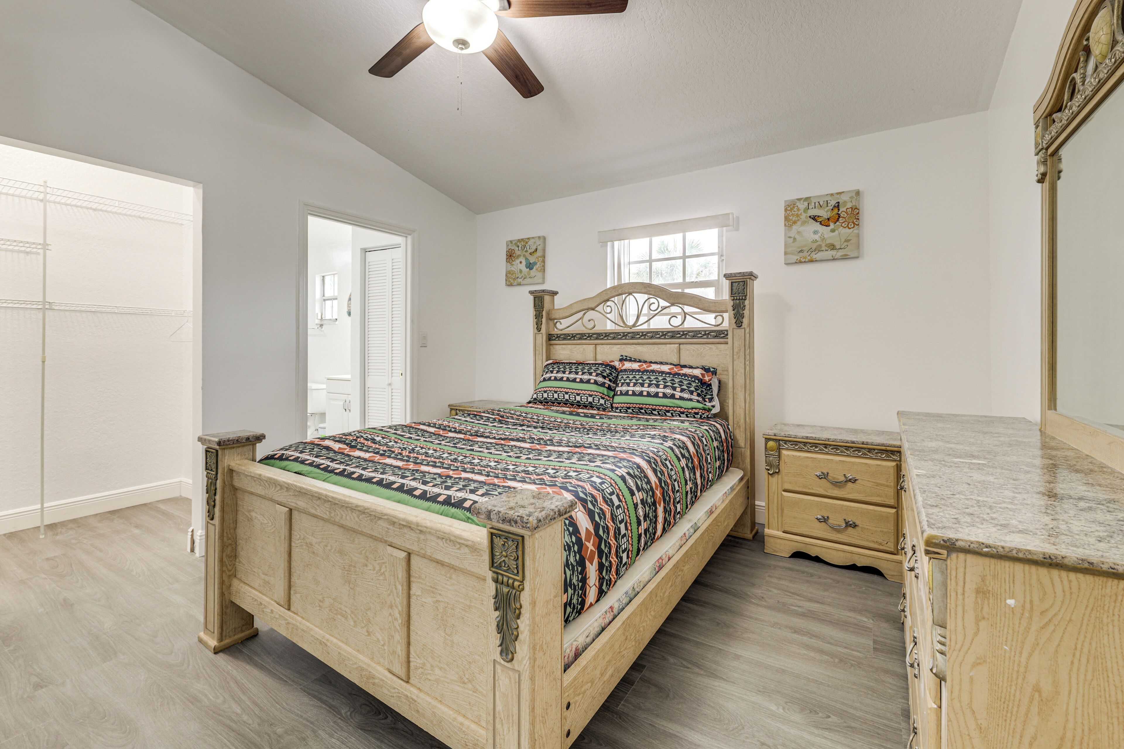 A bedroom with a wooden bed, a nightstand, a dresser, and a ceiling fan.