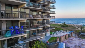 Un hotel de varios pisos con balcones, mobiliario exterior y vista a la playa.