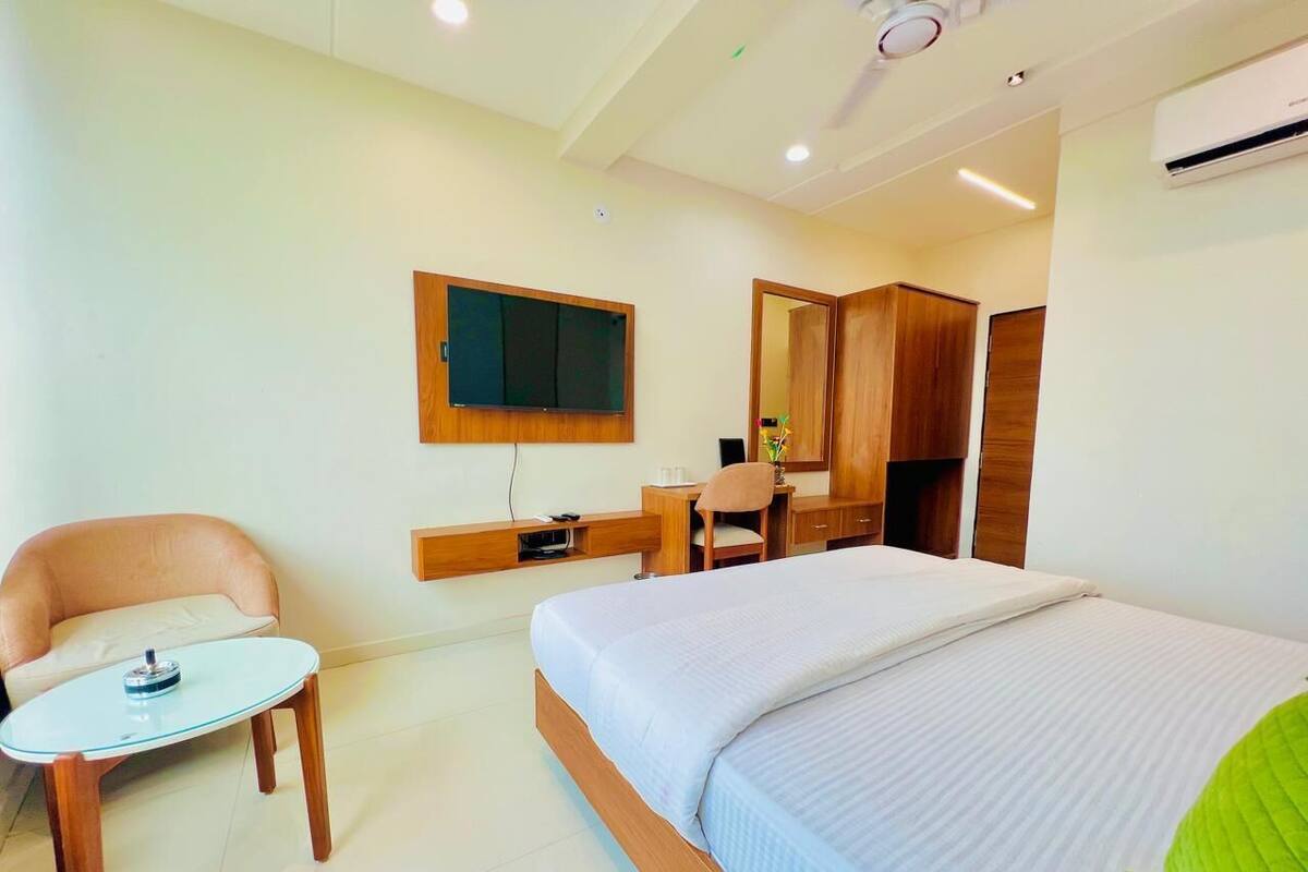 A hotel room with a bed, a desk, a chair, a television, and a wardrobe.