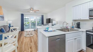 Una cucina moderna con mobili bianchi, lavastoviglie, macchina per il caffè e vista all'esterno.