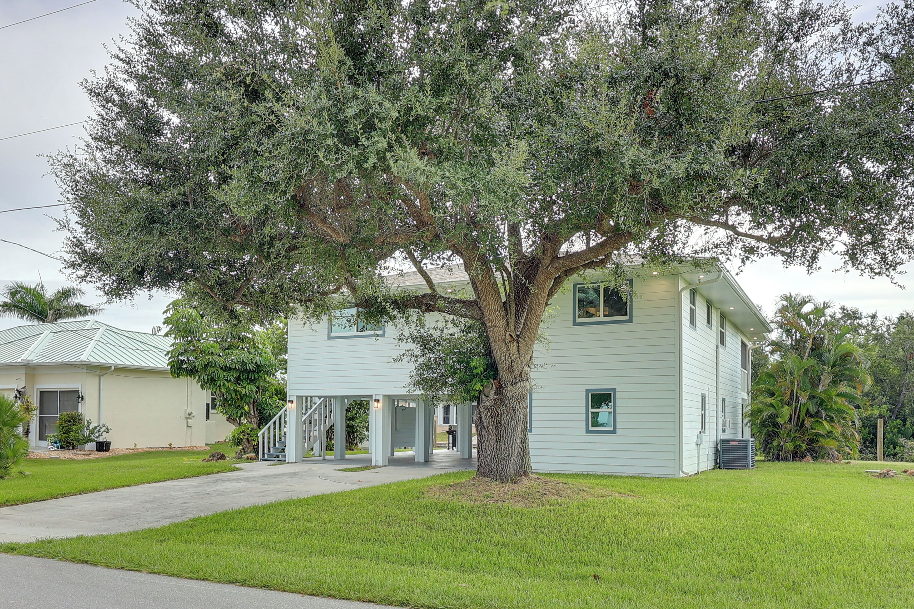 Una casa de dos pisos en azul claro con un árbol grande en la fachada.