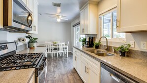 A modern kitchen with white cabinets, a stainless steel stove, a dishwasher, and a window providing natural light. - Pet-friendly Apt 11 Mi to Dtwn San Diego! (Spring Valley)