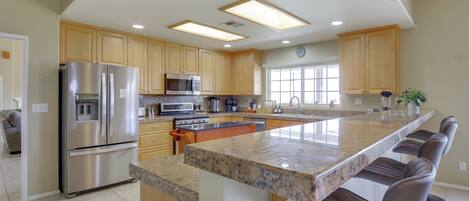 A modern kitchen with stainless steel appliances, a granite countertop, and wooden cabinets.