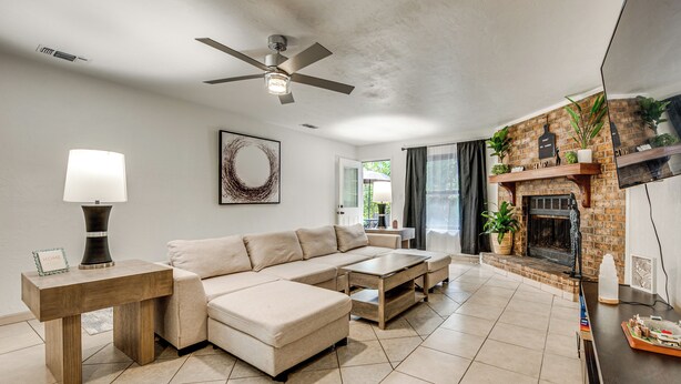 A modern living room with a sectional sofa, a coffee table, a fireplace, and a ceiling fan. - Group-friendly Rental 5 Mi to Dtwn Tallahassee! (Tallahassee)