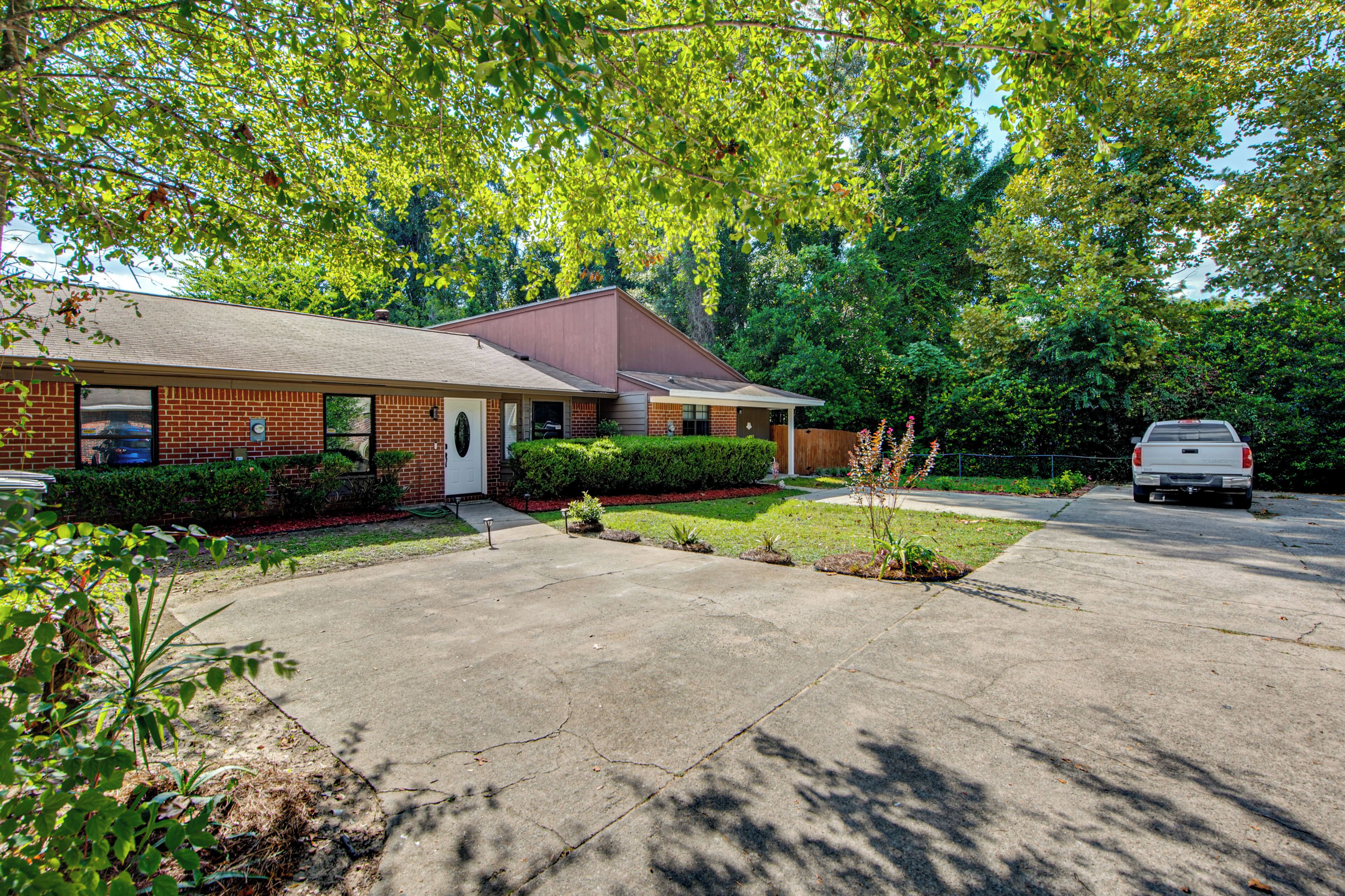 A two-story brick house with a front porch, a driveway, and a white car parked in the driveway.