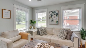 A living room with a beige sofa, a wooden coffee table, and a large window with blinds. - 1 Mi to OKC Fair Park: Family-friendly Apt! (Oklahoma City)