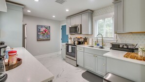 A modern kitchen with white cabinets, stainless steel appliances, and a marble floor. - 1 Mi to OKC Fair Park: Family-friendly Apt! (Oklahoma City)