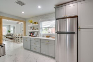 A modern kitchen with a stainless steel refrigerator, white cabinetry, and a window with blinds. - 1 Mi to OKC Fair Park: Family-friendly Apt! (Oklahoma City)