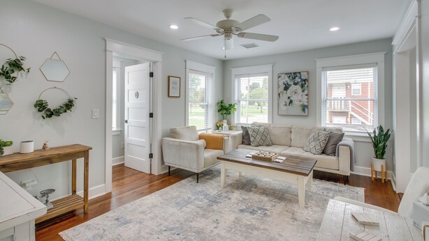 A spacious living room with a ceiling fan, a wooden coffee table, a beige sofa, and a large window providing natural light. - 1 Mi to OKC Fair Park: Family-friendly Apt! (Oklahoma City)