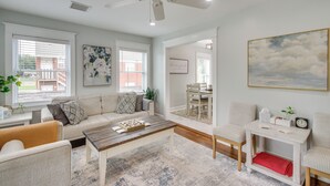 A spacious living room with a sofa, coffee table, and chairs. There is a dining area with a table and chairs visible through an open door. - 1 Mi to OKC Fair Park: Family-friendly Apt! (Oklahoma City)
