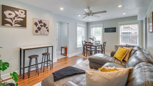 A living room with a leather sofa, a dining table, and two bar stools.