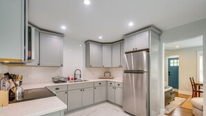 A modern kitchen with white cabinets, a stainless steel refrigerator, and a marble floor.