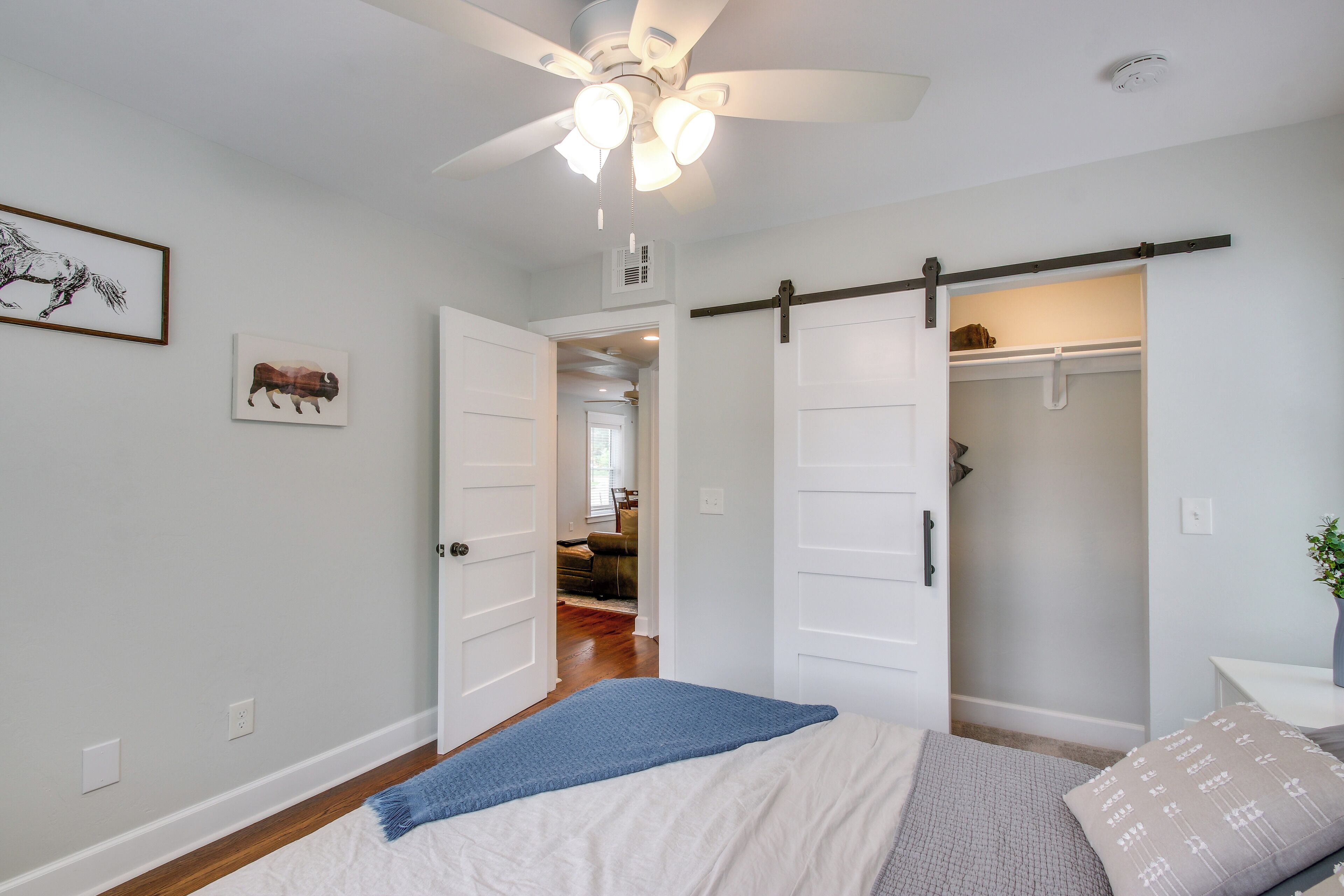 A bedroom with a bed, a ceiling fan, and a sliding closet door.