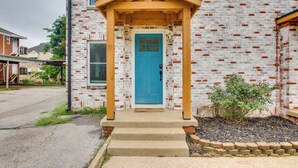 A building with a blue door, a wooden porch, and a brick facade.