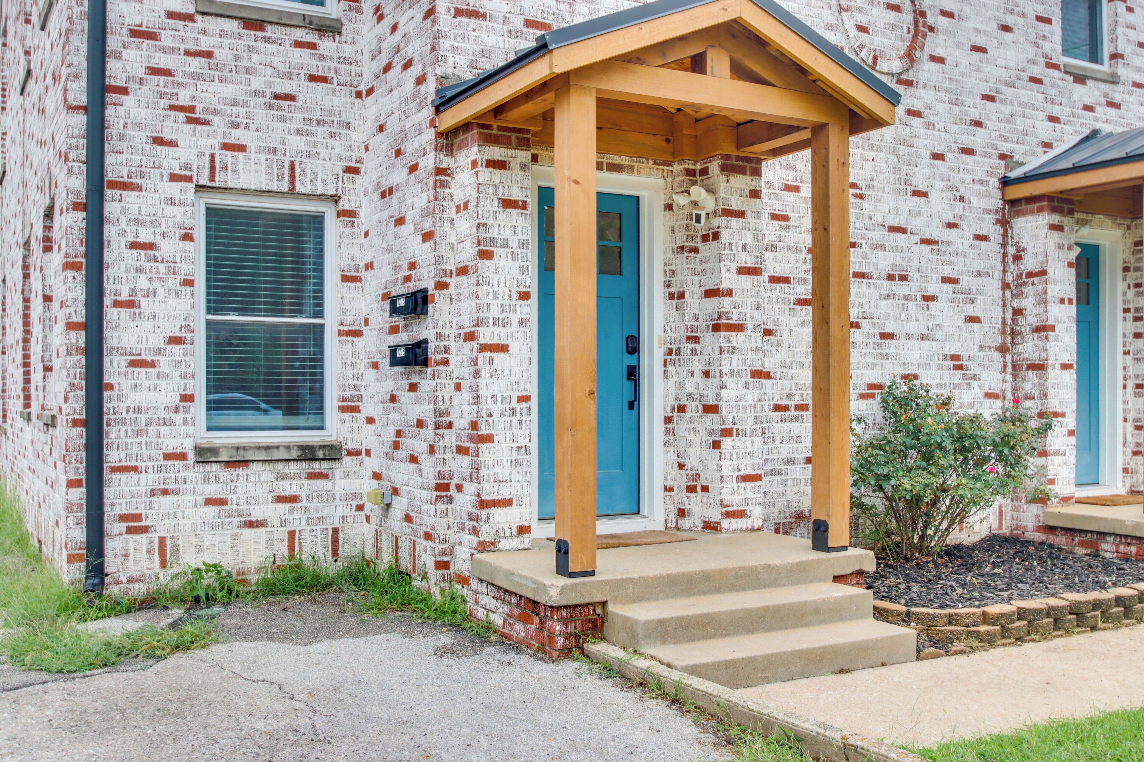 A brick building with a blue door and a wooden porch.