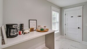 A clean, modern kitchen with a coffee maker, mugs, and a tray of coffee cups.