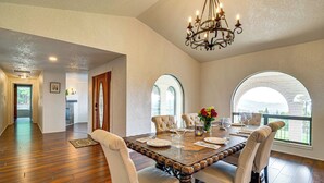 A dining area with a wooden table, four chairs, and a chandelier. - Mtn Views & Hot Tub: Umpqua Valley Villa! (Roseburg)