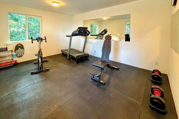 A home gym with a treadmill, stationary bike, and weight bench.