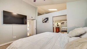 A bedroom with a large bed, a flat-screen TV mounted on the wall, and a closet with a mirror. - Fenced-in Yard: Home < 1 Mi to Lake Ray Hubbard! (Garland)
