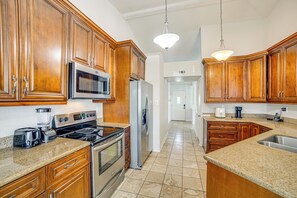A kitchen with wooden cabinets, stainless steel appliances, granite countertops, and pendant lighting.