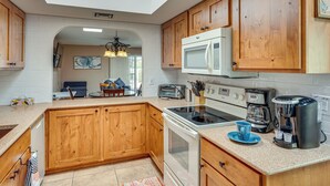 A modern kitchen with wooden cabinets, a microwave, a stove, and a coffee maker. - Quiet Townhome w/ Mountain Views in Green Valley (Green Valley)