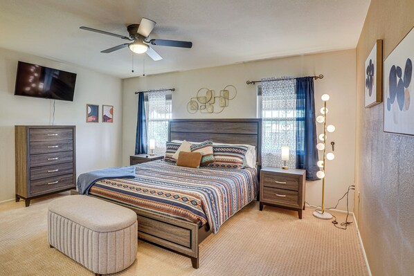 A bedroom with a bed, a dresser, a vanity with lights, a ceiling fan, and artwork on the walls. - Quiet Townhome w/ Mountain Views in Green Valley (Green Valley)