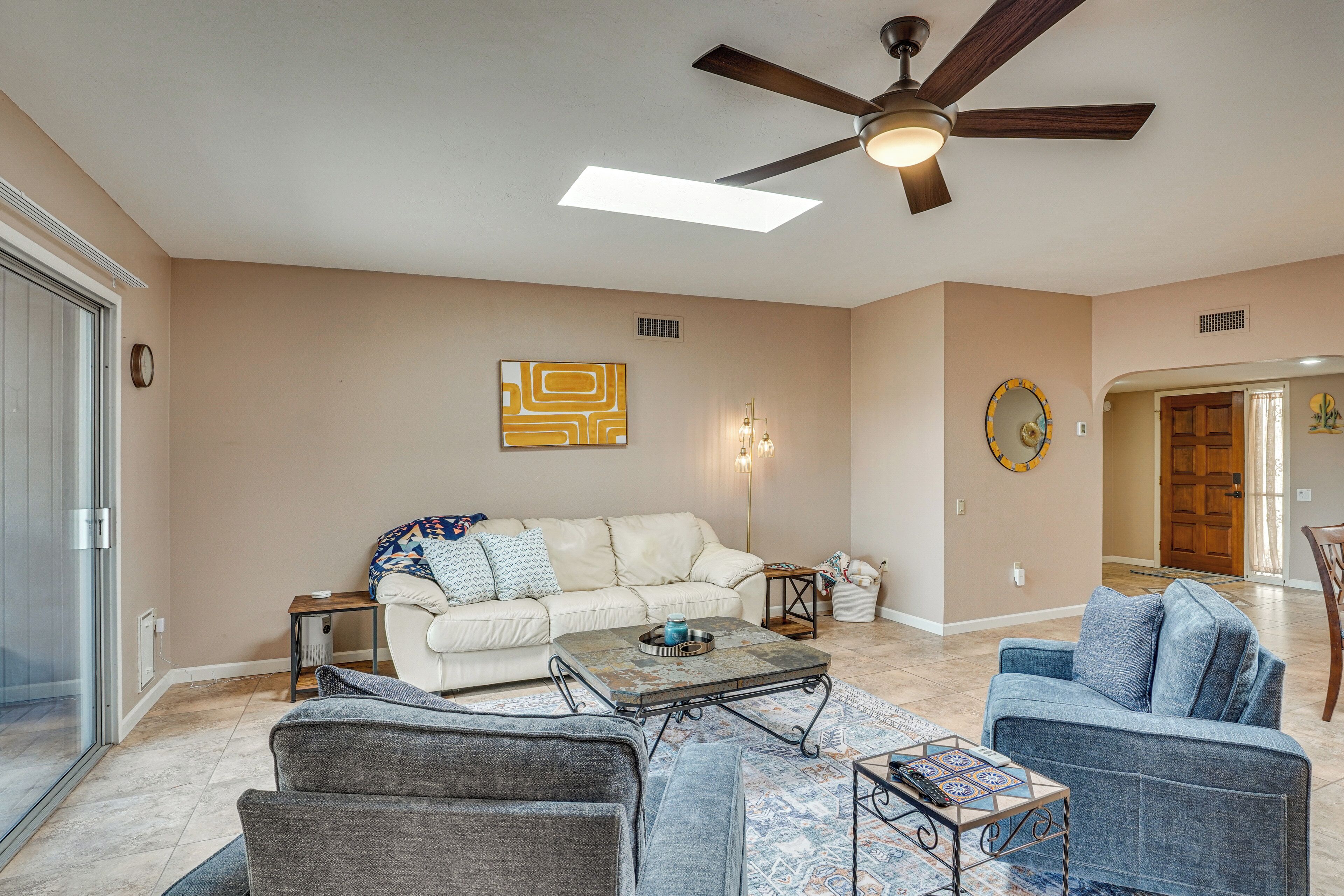 A spacious living room with a ceiling fan, a white sofa, a blue sofa, and a coffee table.